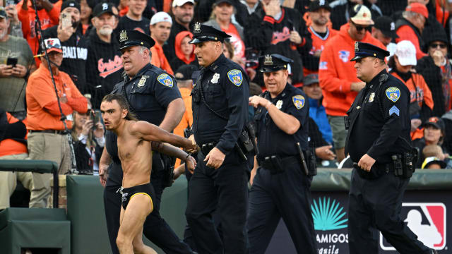 Oct 7, 2023; Baltimore, Maryland, USA; Baltimore police officers escort a fan who ran onto the field during the seventh inning in game one of the ALDS for the 2023 MLB playoffs between the Baltimore Orioles and the Texas Rangers at Oriole Park at Camden Yards. Mandatory Credit: Tommy Gilligan-USA TODAY Sports